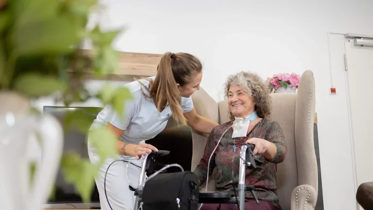Pflegerin mit Patientin im Wohnraum 