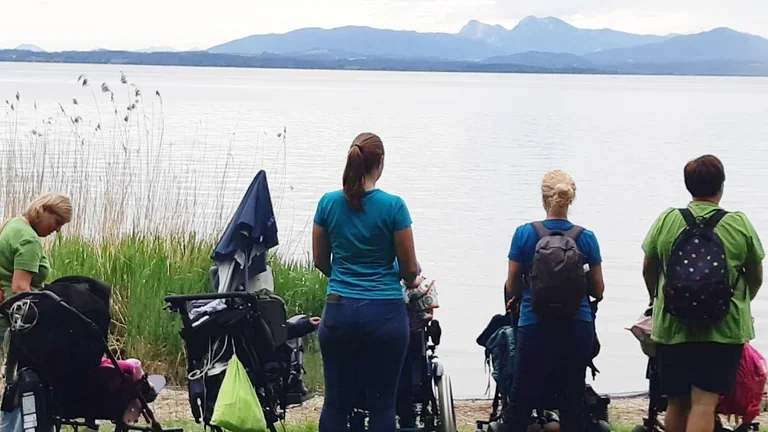 Patientinnen und Pflegerinnen blicken auf einen See