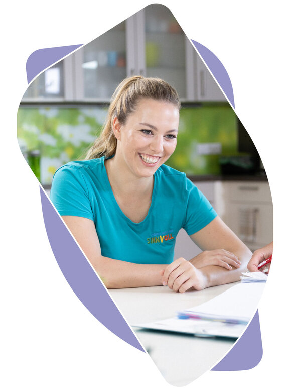 Pflegefachkraft im Gespräch sitzend am Tisch