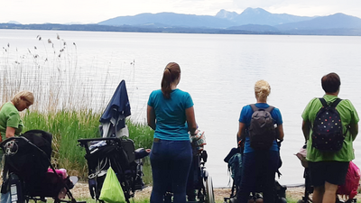 Patientinnen und Pflegerinnen blicken auf einen See